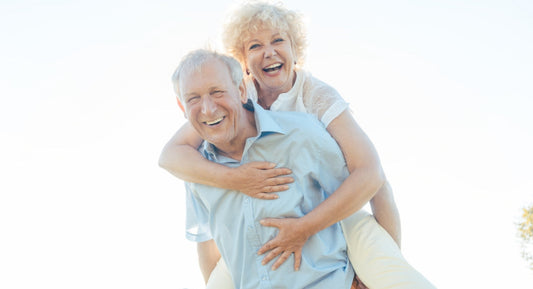 An older woman being given a piggyback ride by an older man