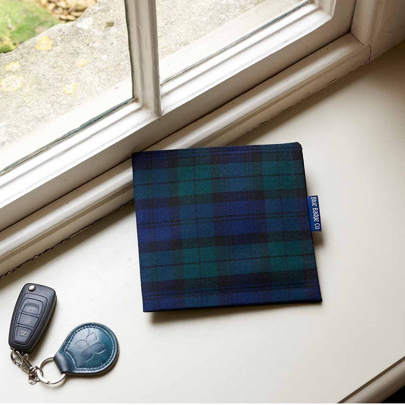 Disabled Blue Badge Wallet in Blackwatch Tartan on a pale pink windowsill, next to a car key on a blue leather fob which has the Blue Badge Co logo embossed on it.