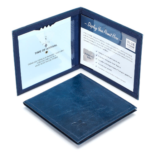 Two Disabled Blue Badge Wallets in Navy leather are pictured. One stands open showing clock display on left behind plastic window, with room to adjust time dial. On the right is a card insert showing place for permit and a hologram safe design. Second, closed wallet lays in front of the open wallet. The leather is a dark navy colour embossed in the bottom right corner with a discreet Blue Badge Co logo.