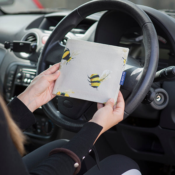 Blue Badge Wallet in Busy Bees fabric is held in two hands against a steering wheel.