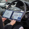 Open Disabled Blue Badge Wallet held in two hands against a steering wheel. The adjustable timer display clock is on the left. On the right is a Devon County Council Disabled Parking Permit with hologram. The acetate window doesn't cover the hologram.