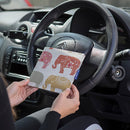The Blue Badge Wallet in Nelly Elephant fabric is held in two hands against the steering wheel of a vehicle.