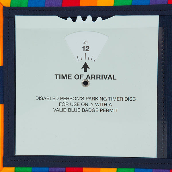 A close up of the timer clock inside the Rainbow Blue Badge Wallet. The acetate window stops before the top of the clock allowing the dial to be turned to adjust displayed Time Of Arrival. An arrow points to the dial numbers. Text below reads TIME OF ARRIVAL. Under that is written Disabled person's parking timer disc for use only with a valid blue badge permit.