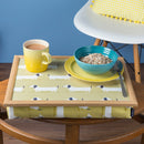 The Sausage Dog lap tray is pictured on a wooden table with a cup of tea and a bowl of cereal on top. There is ample room for the tea mug and breakfast bowl. 